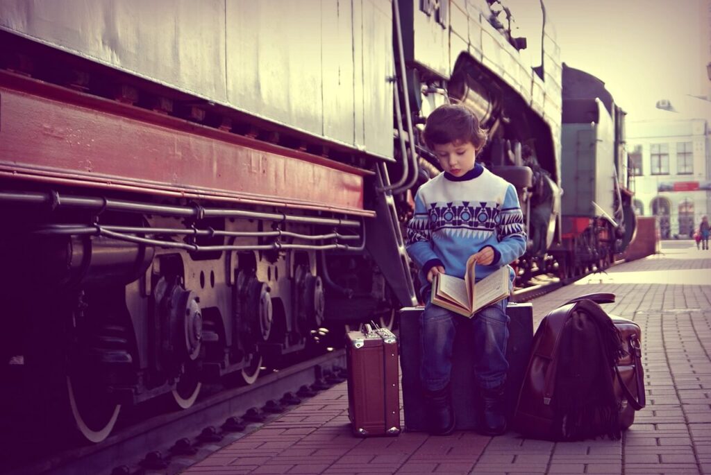 Pojke med resväskor vid tåg på station