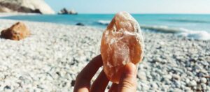 sten i handen, strand i bakgrunden