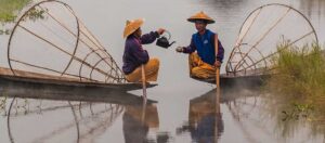 två personer som dricker te i varsin båt på en flod