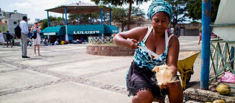 sittande kvinna som skär upp en kokosnöt